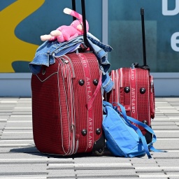 Gepackte Koffer stehen vor dem Terminal des Kassel-Airports, an dessen Fassade der Spruch "Der Sonne entgegen" steht.