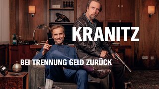 Szenenbild aus der Impro-Serie "Kranitz - Bei Trennung Geld zurück": Ein Mann mit Pistole und einer mit Sektflasche und Gläsern stehen in einem Zimmer.