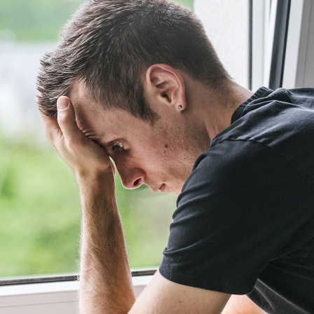 Trauriger junger Mann am Fenster