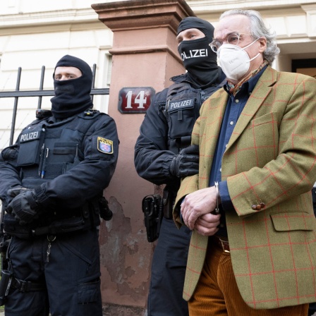Aufnahme 07.02.2022: Bei einer Razzia gegen sogenannte &#034;Reichsbürger&#034; führen vermummte Polizisten, nach der Durchsuchung eines Hauses Heinrich XIII Prinz Reuß (r) zu einem Polizeifahrzeug.
