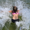 Eine junge Frau springt in einen See und das Wasser spritzt bei ihrem Aufprall zur Seite.