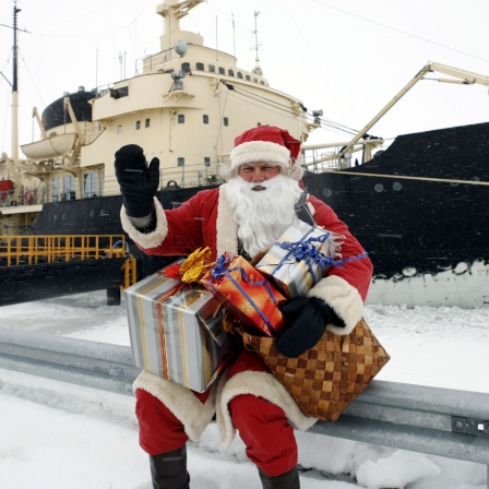 Ein Weihnachtsmann sitzt vor einem Schiff