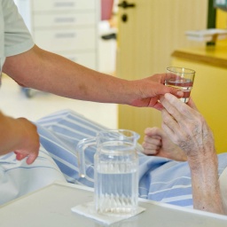 Symbolbild: Eine Pflegekraft gibt einem Menschen im Krankehaus etwas zu trinken (2015)