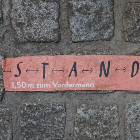 Aufkleber mit den Worten "S T A N D halten" auf Kopfsteinpflaster in Erfurt.
