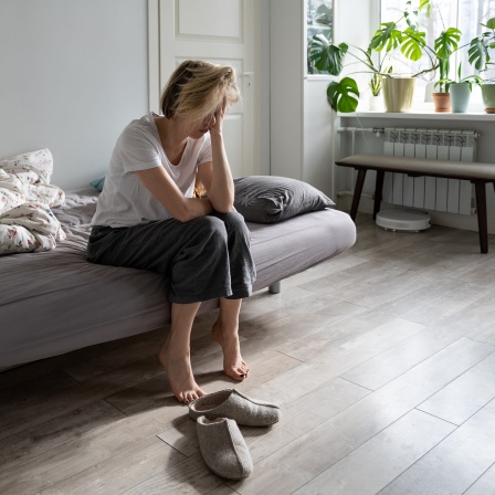 Frau mit Depressionen sitzt auf einem Bett