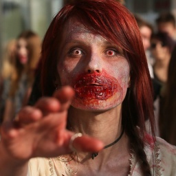 Eine Frau als Zombie kostümiert nimmt am einem Zombie-Walk teil 