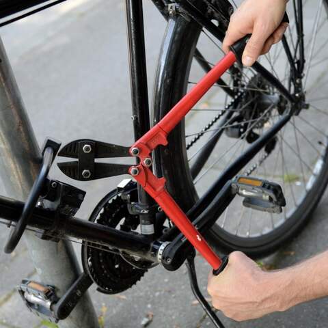 Ein Mann versucht mit einem Bolzenschneider ein Fahrradschloss aufzubrechen.