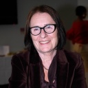 Irina Scherbakowa, eine ältere Frau mit schulterlangen, braunen Haaren und großer, schwarzer Brille, lächelt in die Kamera