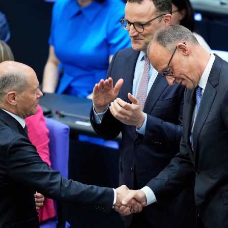 Der Vorsitzende der Christdemokraten Friedrich Merz wird vom scheidenden Bundeskanzler Olaf Scholz nach seiner Wahl zum neuen Bundeskanzler im Deutschen Bundestag beglückwünscht.