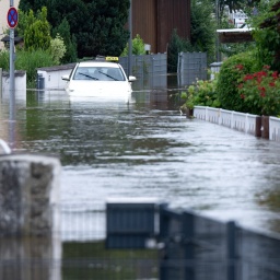 Ein Taxi ist halb im Wasser versunken auf deiner hüfthoch überfluteten Straße mit überfluteten Vorgärten