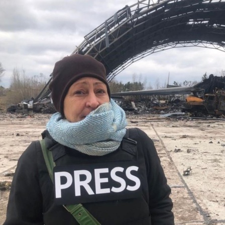 Die ARD-Korrespondentin Silke Diettrich steht vor zerbombten Ruinen 