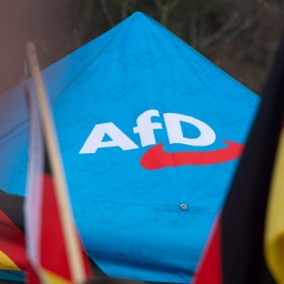 Das Logo der AfD ist bei einer Kundgebung in Düsseldorf neben Deutschlandflaggen auf einem Zeltpavillion zu sehen.