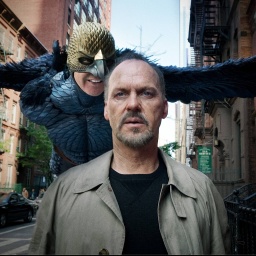 Szenenbild aus &#034;Birdman&#034; mit Michael Keaton im Vordergrund. Direkt hinter ihm fliegt Birdman und flüstert ihm ins Ohr
