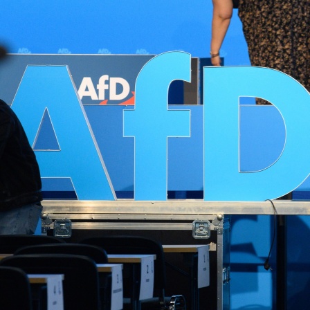 Helfer schieben nach der AfD Europawahlversammlung das AfD Logo aus der Messehalle
