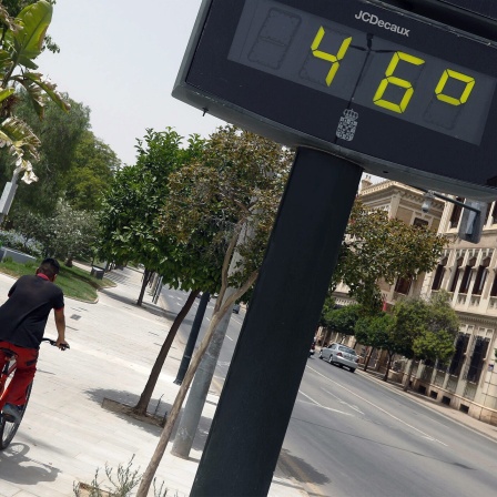 Ein Mann fährt am 12. Juli 2021 in der Stadt Murcia, Spanien, neben einem Thermometer, das 46 Grad anzeigt, Fahrrad. 