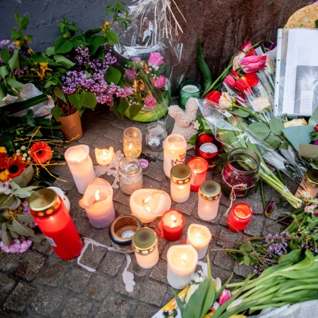 Zahlreiche Blumen und Kerzen stehen in der Innenstadt an einer Hauswand in der Achternstraße, in der am frühen Sonntagmorgen ein Mensch von Schüssen aus einer Polizeiwaffe tödlich verletzt wurde. 