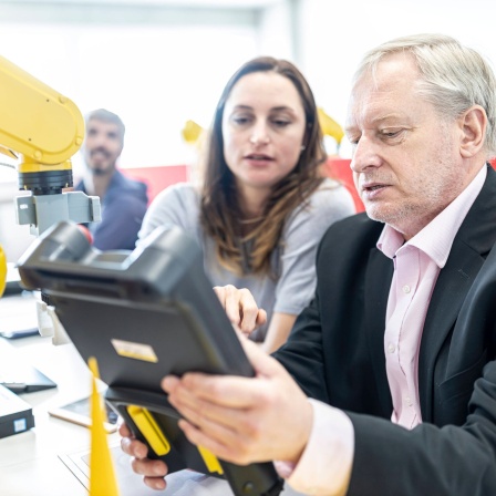 Mann und Frau mit Steuerung eines Industrieroboters