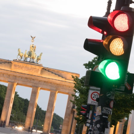 Blick auf eine Ampel vor dem Brandenburger Tor, die gleichzeitig das grüne, das gelbe und das rote Licht zeigt. © picture alliance/dpa | Jörg Carstensen