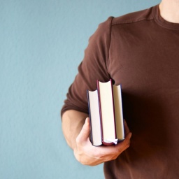 Ein Mann trägt Bücher unter dem Arm.