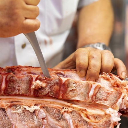 Das Foto zeigt einen Schlachter, der Fleisch schneidet (Symbolfoto).