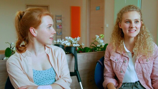 Zwei Mädchen im Gespräch in einem Wartezimmer.