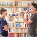 Vater schreit durch ein Megafon aus Zeitungspapier seinen Sohn an.
