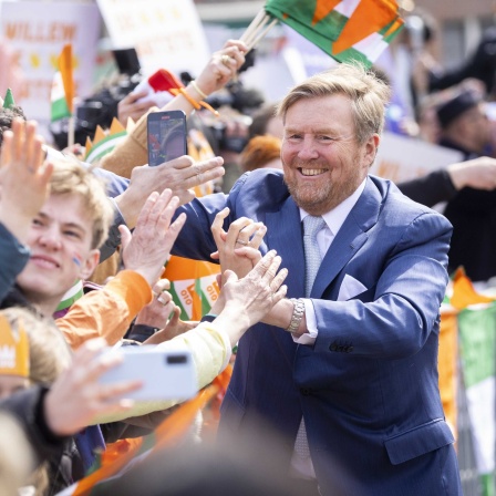 König William Alexander begrüßt beim Königstag in den Niederlanden die Menschen, die ihm zujubeln. Viele sind orange gekleidet.