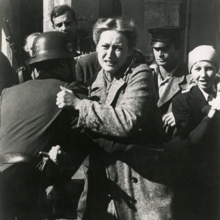 Standfoto aus der Serie "Holocaust", auf dem Meryl Streep von einem Soldaten mit Stahlhelm festgehalten, während sie versucht, sich mit schmerz verzerrtem Gesicht loszureißen.