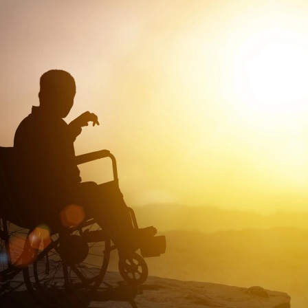 Person im Rollstuhl schaut in die Sonne 