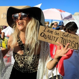 Eine Demonstrantin hält ein Schild hoch mit der Aufschrift "I am the Solution - Quality Tourism" bei einer Demonstration gegen den Massentourismus auf Mallorca.