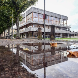 Das Bundesverfassungsgericht in Karlsruhe spiegelt sich in einer Pfütze wider. 