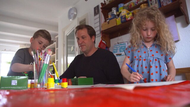 Vater mit kleinem Sohn und kleiner Tochter beim Malen an einem Tisch