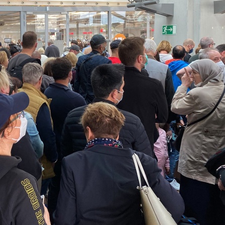 Zahlreiche Passagiere warten vor der Sicherheitskontrolle am Flughafen.