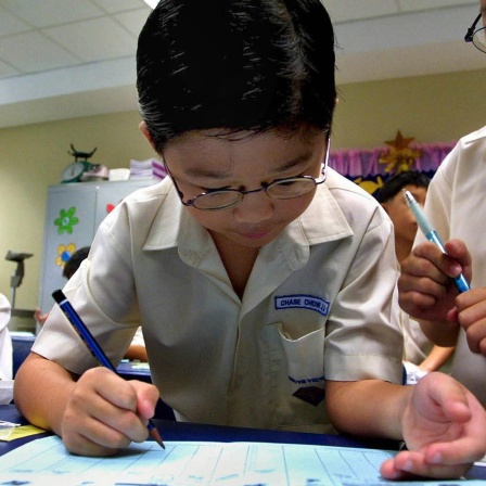 Archivbild: Grundschüler in Singapur machen Eintragungen in ein Heft und sehen dabei sehr konzentriert aus.