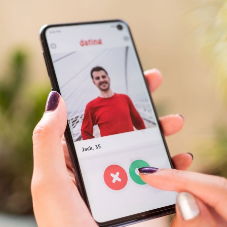 Frau schaut auf Dating-App auf ihrem Smartphone