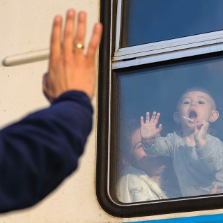 Ein Mann winkt vor einem Zug nach Polen am Bahnhof von Lwiw seinem Kind zum Abschied; © SOPA Images/ZUMA Press Wire/Mykola Tys