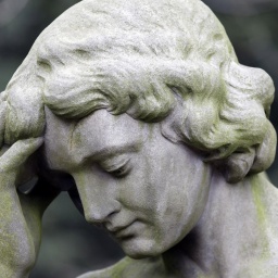 Der Kopf einer Statue eines nachdenklichen Engels, der sich mit der Hand an die Stirn fasst
