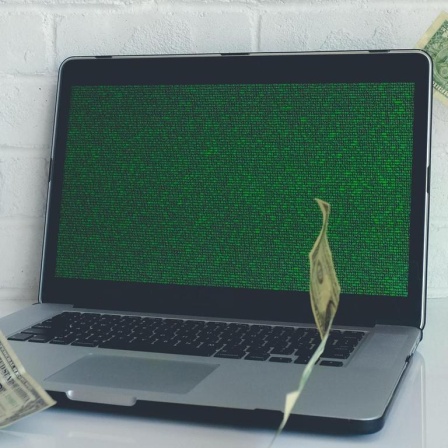 Geldscheine fliegen um einen Laptop herum