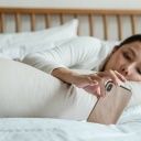 Frau im Bett schaut auf ihr Handy