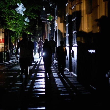 Menschen gehen in Granada während eines Stromausfalls in der Dunkelheit eine Straße entlang.