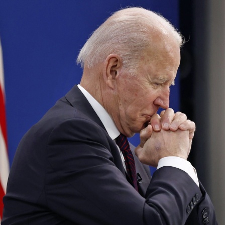 US-Präsident Joe Biden mit sitzt mit gefalteten Händen in einer Konferenz 