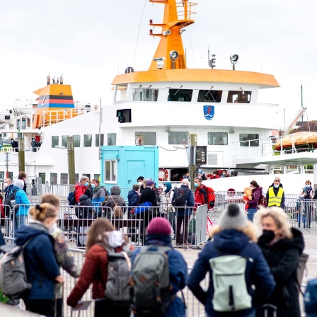 Zahlreiche Touristen warten im Fährhafen in Bensersiel vor der Überfahrt zur Insel Langeoog auf den Zugang zum Fährschiff.
