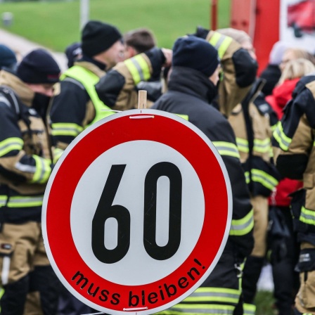 Feuerwehrleute stehen vor dem NRW-Landtag und demonstrieren für den Erhalt der Rentenaltersgrenze von 60 Jahren.