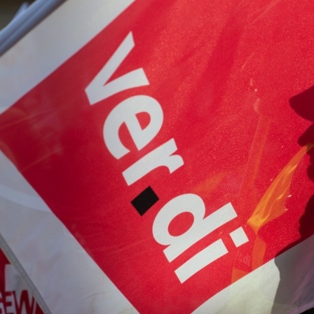 Der Schatten eines Teilnehmers am Warnstreik fällt auf eine Fahne der Gewerkschaft Verdi. 