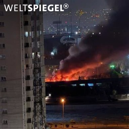 Ein Gebäude steht bei Nacht in Flammen und es steigt dichter, dunkler Rauch auf