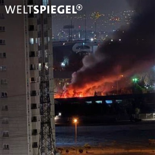 Ein Gebäude steht bei Nacht in Flammen und es steigt dichter, dunkler Rauch auf