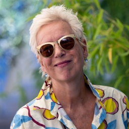 Frau mit Sonnenbrille lacht in die Kamera