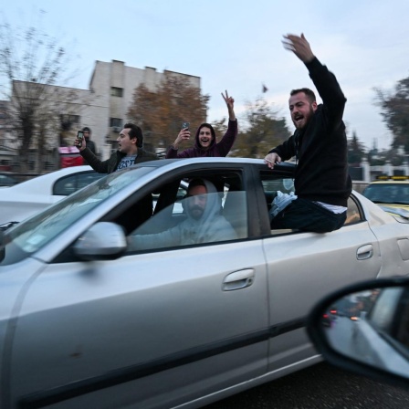 Menschen in einem Auto jubeln. Die Aufnahme ist aus der syrischen Hauptstadt Damaskus.