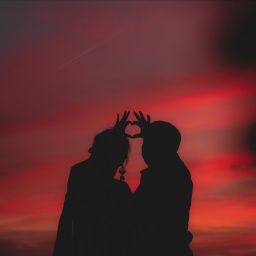 Eine Gestalt eines Paares vor einem roten Sonnenuntergang