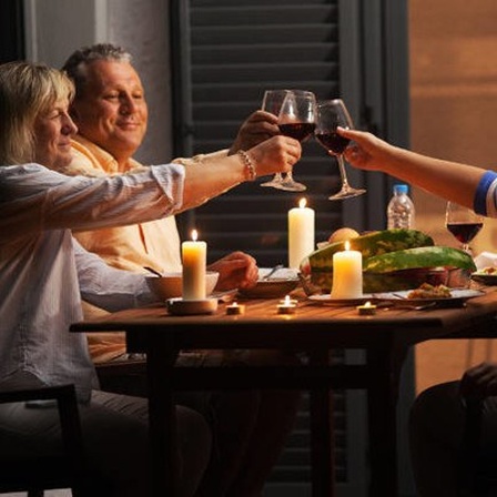 Drei Personen am Tisch mit einem Glas Wein in der Hand